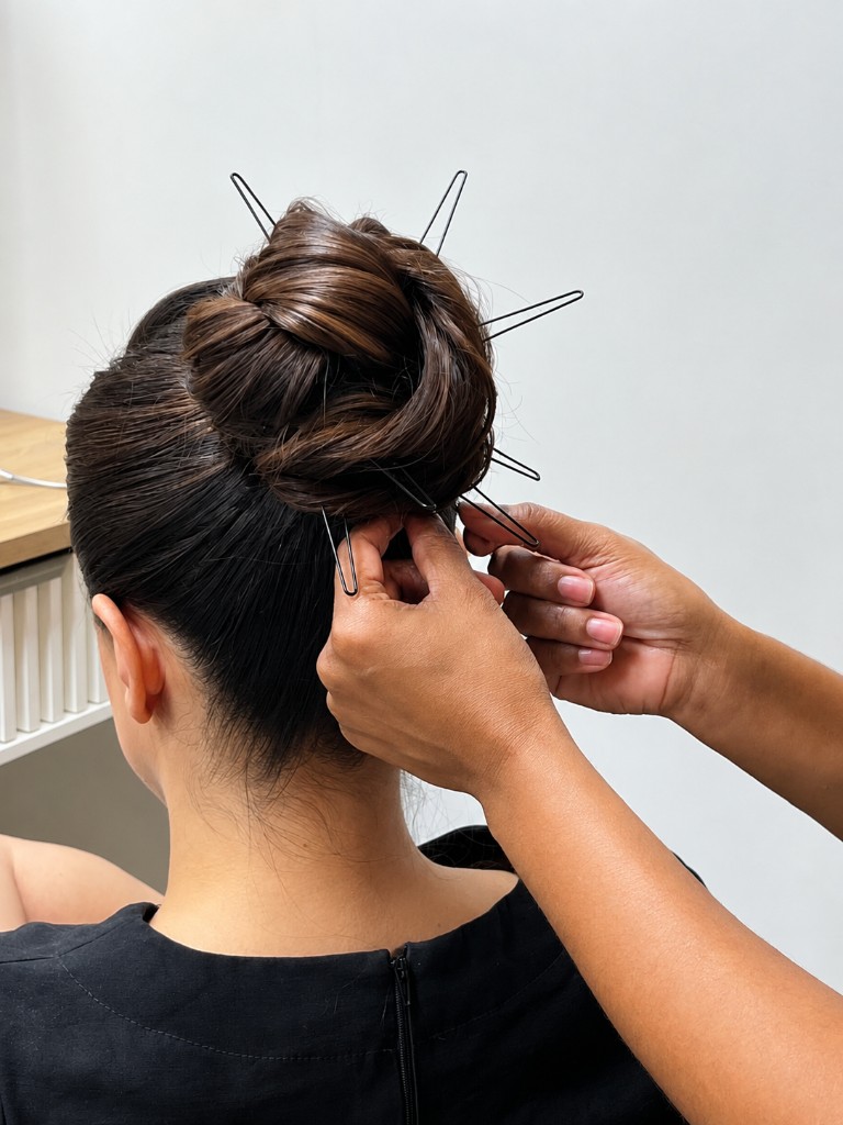 Penteado coque elegante sendo finalizado no Paula Fernanda Studio.